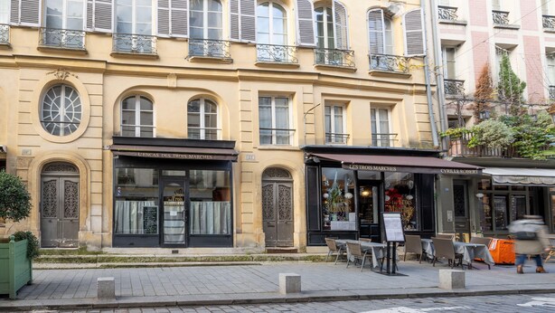 A building with multiple windows, a storefront with outdoor seating, and a green planter. - Charming studio in Versailles - Welkeys (Versailles)