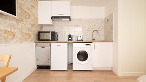 A compact kitchen with a microwave, toaster, and washing machine. - Charming studio in Versailles - Welkeys (Versailles)