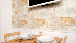 A dining table set with plates, glasses, and cutlery, with a leopard print wallpaper in the background. - Charming studio in Versailles - Welkeys (Versailles)