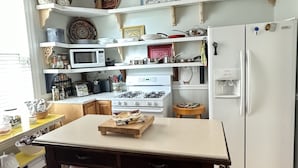 Una cocina con armarios de madera, un refrigerador blanco, un microondas y una estufa a gas.