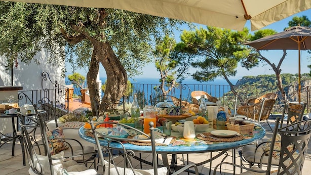 An outdoor dining area with a round table set for four, surrounded by wicker chairs.