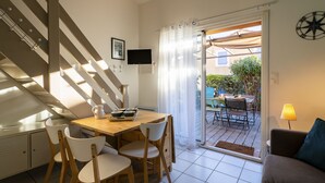 A modern kitchen with a dining area, a staircase, and a view of the outdoor patio. - Beau Soleil by Interhome (Narbonne-Plage)