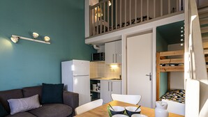 A compact living space with a kitchenette, a dining area, and a bunk bed. - Beau Soleil by Interhome (Narbonne-Plage)