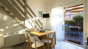 A modern kitchen with a dining area, a staircase, and a view of the outdoor patio. - Beau Soleil by Interhome (Narbonne-Plage)
