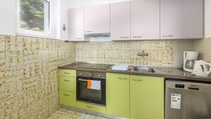 Una cocina con gabinetes verdes, un lavamanos de acero inoxidable, una cafetera Bosch y un lavavajillas Koncar.