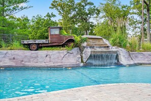 Ein Schwimmbecken mit Wasserfall und ein alter Lastwagen, der daneben geparkt ist.