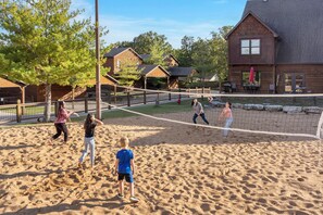 Ein Sandvolleyballfeld mit hölzerner Umzäunung, umgeben von Wohnhäusern und Bäumen.