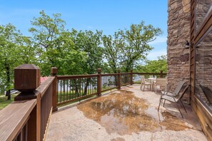 Eine Holzterrasse mit einer Steinmauer, Gartenmöbeln und Blick auf Bäume und Wasser.