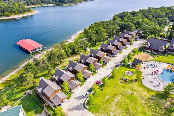 A lakeside residential area with multiple houses, a dock, and a swimming pool. - Beautiful Lakefront Retreat w/ Sloping Shoreline, Community Aminities & Free Attractions (Branson)
