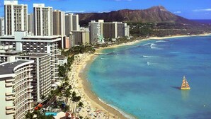 A coastal cityscape with high-rise hotels, a beach, and a sailboat.