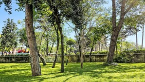 A park with trees, grass, and a concrete wall. - Beautiful apartment in villa for 6 guests with pool, A/C, WIFI, TV and terrace (Aurisina Cave)