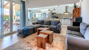 A modern living room with a sectional sofa, two wooden coffee tables, and a patterned rug. - Augusta by Interhome (Rovinj/Žminj)