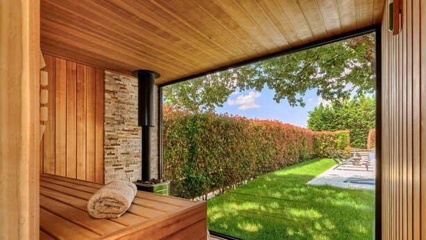 A sauna with a wooden bench, a stone wall, and a black chimney. - Augusta by Interhome (Rovinj/Žminj)