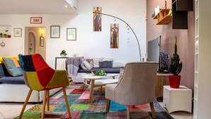 A modern living room with a sofa, chairs, a coffee table, and a colorful rug. There are framed pictures on the wall, a plant, and a TV on a stand. - Rive Droite by Interhome (La Bernerie-en Retz)