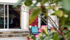 A patio area with outdoor seating and a view of a building with a red door. - Rive Droite by Interhome (La Bernerie-en Retz)