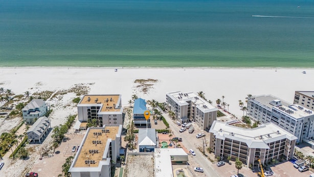 Ein Luftbild eines Küstenhotels mit mehreren Gebäuden, einem Strand im Vordergrund und dem Ozean im Hintergrund.