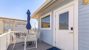 Eine überdachte Terrasse mit Tisch und Stühlen, eine Tür mit Fenster und eine blaue Matte am Eingang.