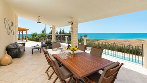 Una terrazza con tavolo e sedie in legno, un vaso con fiori e vista sul mare.
