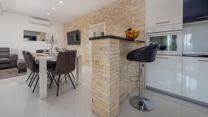 A modern kitchen with a built-in oven, a dining area with a table and chairs, and a TV mounted on the wall.