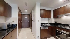A modern kitchen with dark wooden cabinets, stainless steel appliances, and a black countertop.