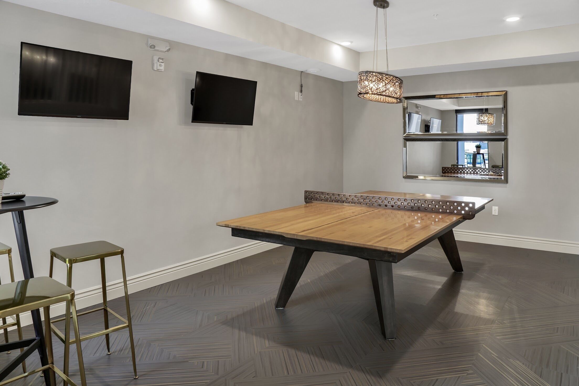 Een moderne woonkamer met een houten salontafel, een flatscreen televisie, een hanglamp en een spiegelwand.