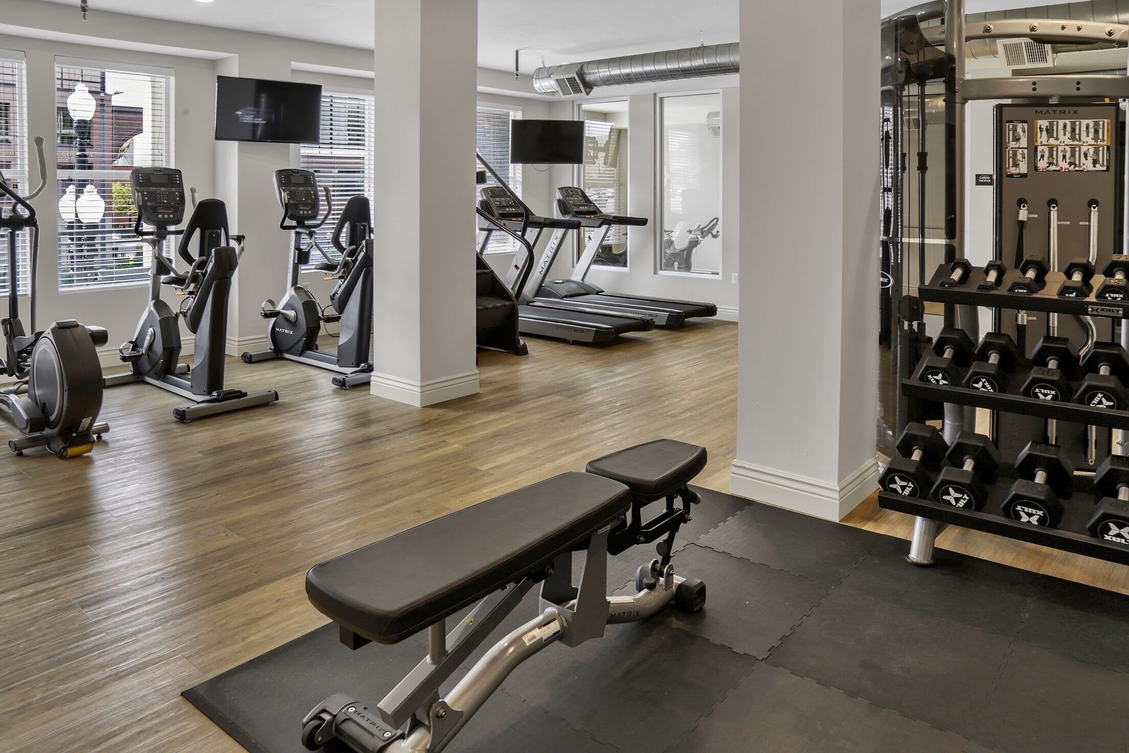 A gym with treadmills, elliptical machines, and a bench.