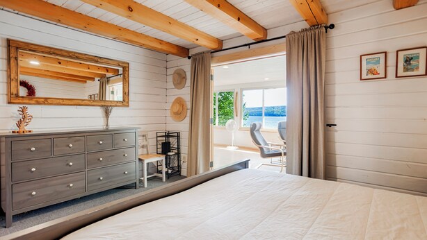 Quarto com cama grande, penteadeira, espelho e vista para o exterior.