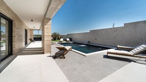 A modern outdoor pool area with lounge chairs and a view of the sea. - Lovely home in Miranje Donje (Miranje Donje)