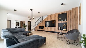 A modern living room with a sectional sofa, a dining table, and a staircase. - Lovely home in Miranje Donje (Miranje Donje)