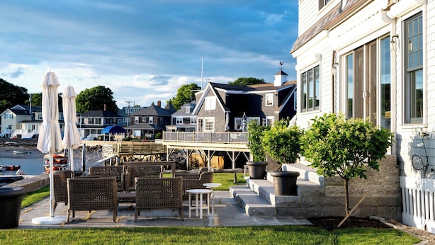A waterfront property with outdoor seating, a dock, and a view of the water. - Luxury oceanfront 5 bedroom, 5.5 bath private dock overlooking Mothers Beach! (Kennebunk)