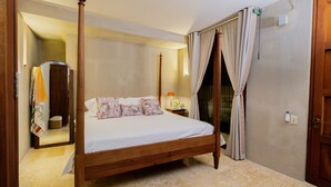 A four-poster bed with a wooden frame, a nightstand with a lamp, and a door with a curtain. - Luxury 5BR House W Jacuzzi & Pool (Cartagena)
