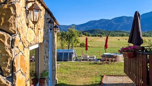 A stone building with outdoor seating, a hot tub, and a view of mountains. - Awesome home in Lovinac (Lovinac)