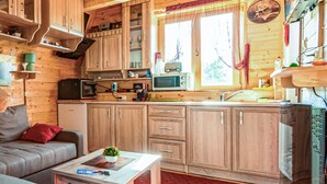 A cozy cabin-style kitchen with wooden cabinets, a microwave, a coffee maker, and a sink. - Awesome home in Lovinac (Lovinac)