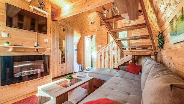 A cozy cabin interior with a sofa, a coffee table, a fireplace, and a staircase. - Awesome home in Lovinac (Lovinac)