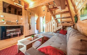A cozy cabin interior with a sofa, a coffee table, a fireplace, and a staircase. - Awesome home in Lovinac (Lovinac)