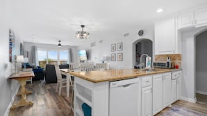 A modern kitchen with white cabinetry, a granite countertop, and a built-in dishwasher. - La Mirage Condo 112 Beachfront Resort Condominiums with Private Boardwalk (Port Aransas)