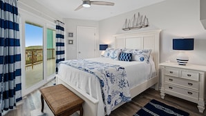 A bedroom with a bed, a nightstand, a bench, and a view of the outdoors. - La Mirage Condo 112 Beachfront Resort Condominiums with Private Boardwalk (Port Aransas)