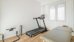 A room with a treadmill, a massage table, and a massage chair.