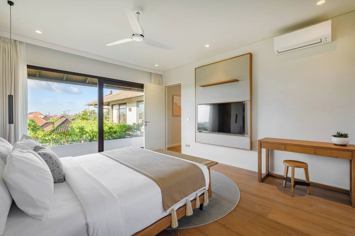 Un dormitorio moderno con cama, escritorio y televisor.