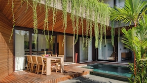 A modern house with a wooden deck, a pool, and hanging plants.