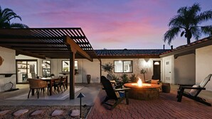 A patio area with a fire pit, outdoor seating, and a pergola structure.
