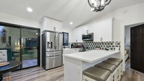 A modern kitchen with a central island, stainless steel appliances, and a large window overlooking a garden.