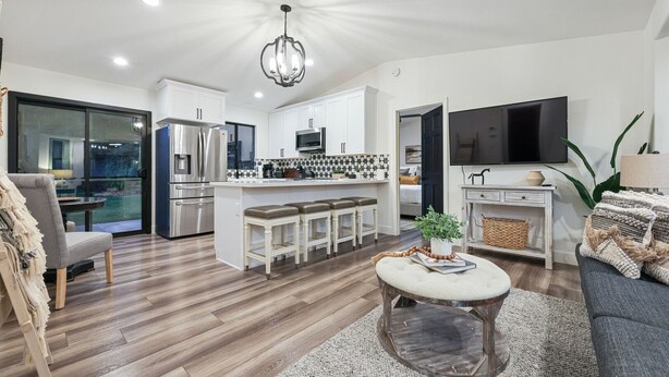 A modern kitchen with white cabinets, stainless steel appliances, and a central island with stools.