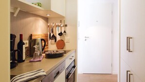 A narrow kitchen with white cabinetry, a wooden countertop, and a built-in oven.