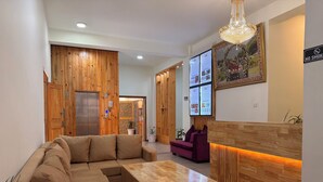 A modern reception area with a wooden reception desk, a large sectional sofa, and a small purple sofa. - Norbu Healing Hotel (Thimphu)