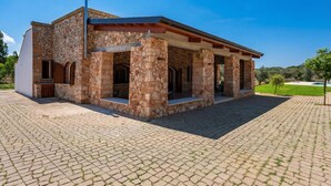 Un bâtiment en pierre doté d’un patio couvert, d’une cheminée et d’une cour pavée.