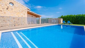Piscina com muro de pedra e área de varanda coberta.