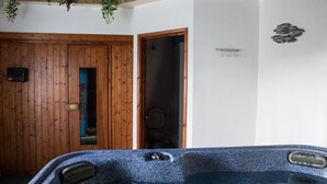 Una habitació amb una porta de fusta, un bany amb vàter i una banyera d'hidromassatge.