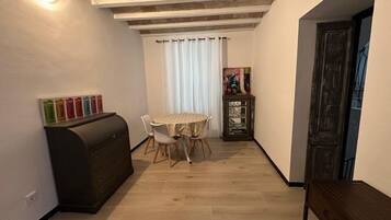 Ein schmaler Flur mit Esstisch und Stühlen, einem dunklen Schrank und einer Tür auf der rechten Seite.