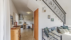 Un salón amplio con sofá, una escalera y una cocina al fondo.